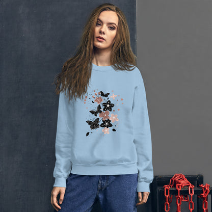 Woman wearing a light blue sweatshirt with a black and pink floral butterfly design on the chest, standing in front of a dark textured wall.