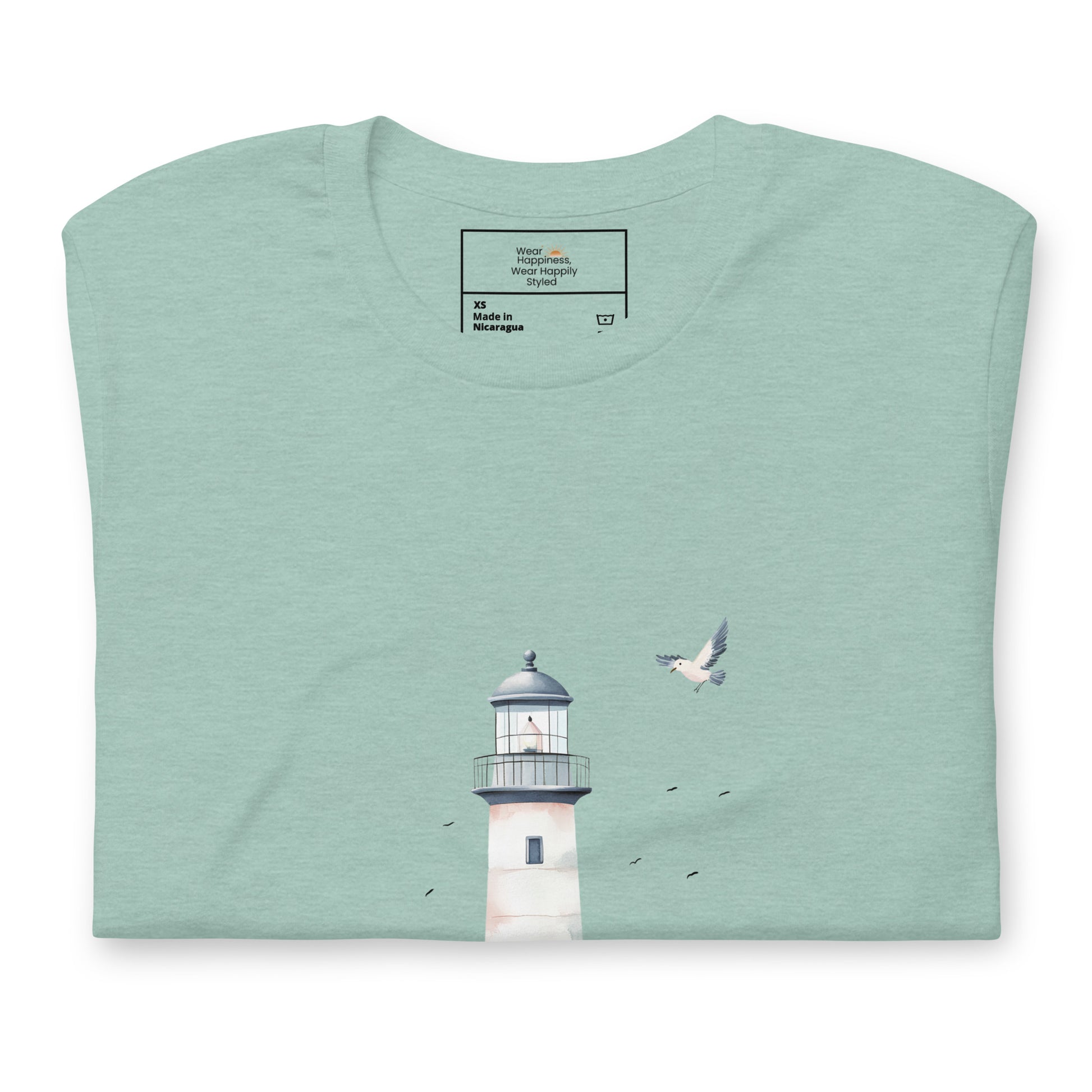 Flat-lay of a folded dusty blue-colored t-shirt featuring a minimal lighthouse and seagull design, styled for a calming, nature-inspired mom aesthetic.