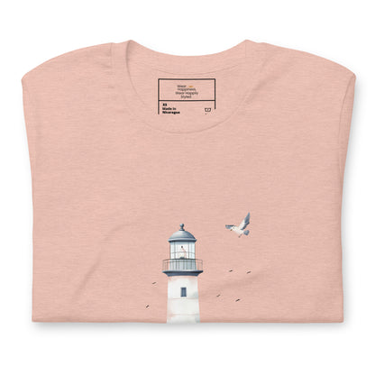 Flat-lay of a folded peach-colored t-shirt featuring a minimal lighthouse and seagull design, styled for a calming, nature-inspired mom aesthetic.