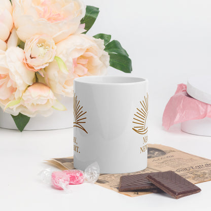 White ceramic mug with gold sun rays and partial text, styled with flowers, candy, and chocolate on a white table.
